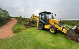 A yellow tractor is parked on a grassy hill, near a path. AI generated content