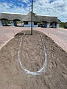 A white outline of a male genitalia is drawn on a dirt field. AI generated content