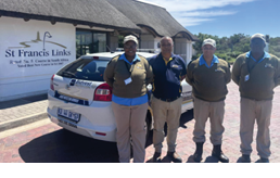 Four people are standing in front of a white car. AI generated content