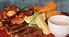 A plate of food with a steak, fried fish, and fries. AI generated content