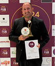 A man in a black suit holds a plaque with a gold emblem. AI generated content