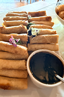 A plate of food is on a table, including a bowl of sauce and a stack of food. AI generated content