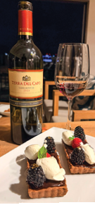 A bottle of wine and a glass of wine are on a table with a plate of food. AI generated content