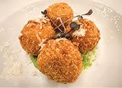 A plate with four pieces of food, possibly meatballs, covered in powdered sugar and garnished with green leaves. AI generated content