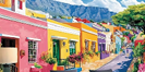 A painting of a street in a colorful town with a mountain in the background. AI generated content