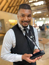 A man wearing a black vest and tie is holding a cell phone. AI generated content